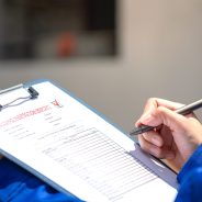An architect is checking on house building quality checklist form to inspecting the progress with building house as blurred background. Construction industrial working scene, close-up.